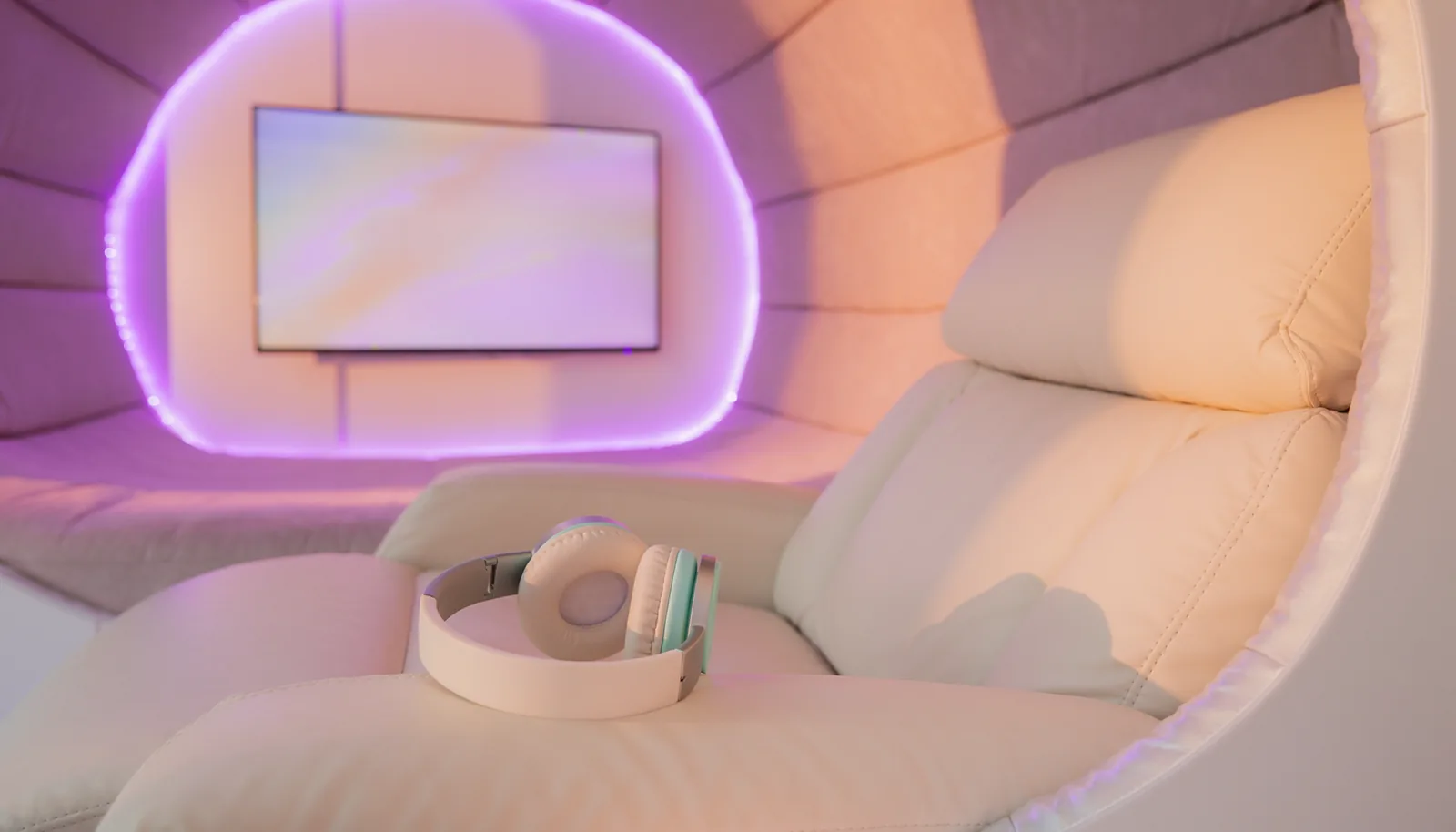Inside a La Vida Rose soundproof pod &mdash; a plush cream recliner with premium headphones, a wall-mounted screen and soft lilac LED lighting